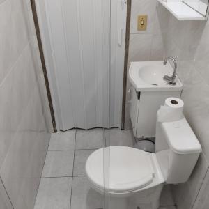 a white bathroom with a toilet and a sink at Acomodações Casa 2 in Cananéia