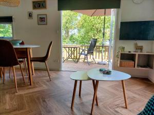 sala de estar con 2 mesas y balcón en Erfgoed de Boemerang - Chalet Alpaca, en Meppen