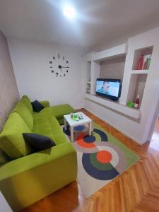 sala de estar con sofá verde y TV en Apartman Stil, en Višegrad
