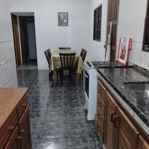 a kitchen with a table and a white stove top oven at Acomodações Casa 2 in Cananéia