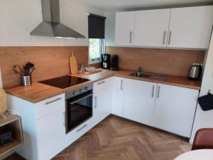 cocina con armarios blancos y fogones en Erfgoed de Boemerang - Chalet Alpaca, en Meppen