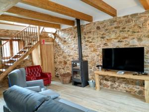 a living room with a stone wall and a tv at Casas rurales Villa la Roza in La Utrera