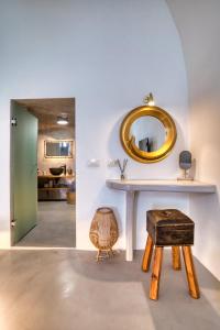 Habitación con mesa, espejo y taburete. en La Ponta Apartments en Akrotiri