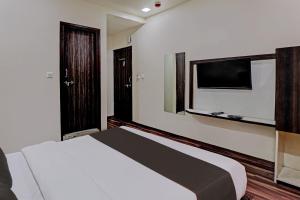 a bedroom with a bed and a flat screen tv at Collection O Hotel Royal Inn in Ahmedabad