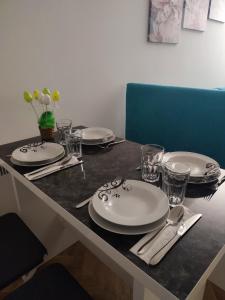 a table with plates and glasses on top of it at Apartman PINA Vrnjacka Banja in Vrnjačka Banja