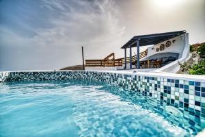 una piscina con una piscina de azulejos azules y blancos en La Ponta Apartments en Akrotiri