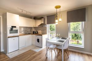 a kitchen with white cabinets and a table and chairs at TheHouse - Apartment Kamenitza in Velingrad