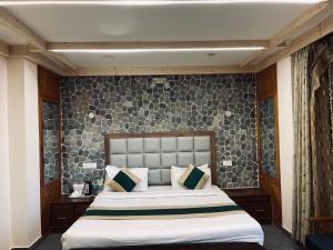 een slaapkamer met een groot bed voor een muur bij The Himalayan Escape in Mundaghat 