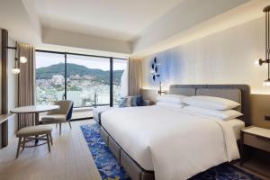 長崎市にある長崎マリオットホテルの大きなベッドとテーブルが備わるホテルルームです。
