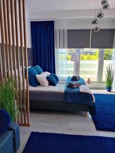 a bedroom with a bed with blue pillows and a window at Apartamenty MAX blisko Energylandia in Ryczów