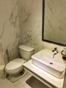 a white bathroom with a toilet and a sink at Diamond Park Inn Chiangrai & Resort in Chiang Rai