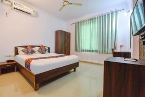 a bedroom with a bed and a flat screen tv at FabHotel Springs in Sangolda