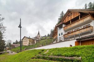 a building on a hill with a church in the background at Apartments Mirabell in Livinallongo del Col di Lana