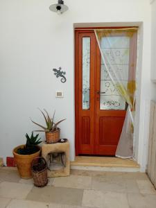 una puerta roja en una habitación blanca con macetas en Margy House, en Morciano di Leuca