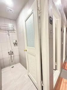 a white bathroom with a shower and a door at Economy Class Hostel in Dayuan