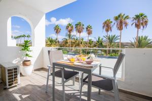 una mesa y sillas en un balcón con palmeras en Palm Beach Fuerteventura en Tarajalejo