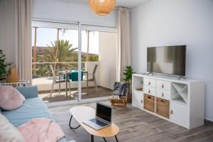 sala de estar con sofá y mesa con ordenador portátil. en Palm Beach Fuerteventura en Tarajalejo