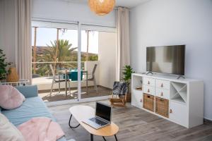 a living room with a couch and a laptop on a table at Palm Beach Fuerteventura in Tarajalejo