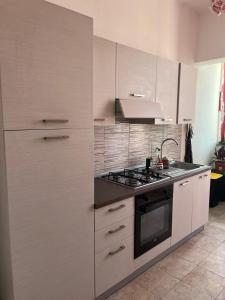 a kitchen with white cabinets and a stove at Casa GIULIVA in Alessandria