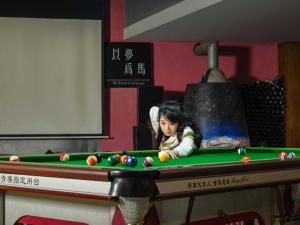 una joven jugando al billar en una mesa en Zhangjiajie Yeah Hostel, en Zhangjiajie