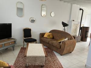 een woonkamer met een bruine bank en een tv bij La Sauveroise in Saint-Sauveur-en-Puisaye