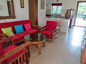 uma sala de estar com um sofá vermelho, cadeiras e uma mesa em Villa Mayfair em Cavelossim