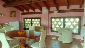 a dining room with a wooden table and white chairs at B&B IL Loto BIKE FRIENDLY in Vailate
