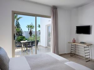 a bedroom with a bed and a balcony with a table at Atlantica Panthea Resort in Ayia Napa