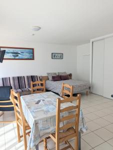 un salon avec une table, des chaises et un canapé dans l'établissement Appart' avec grande terrasse vue mer -50m plage et du sentier de randonnée, à Planguenoual 24 autres photos