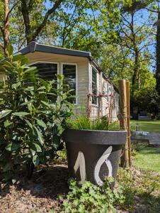 een pot met planten voor een klein huisje bij Ruim Chalet, midden in het bos! in Nunspeet