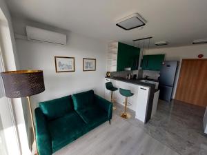 a living room with a green couch and a kitchen at Krapkowice Odrzańskie Tarasy in Krapkowice +19 photos