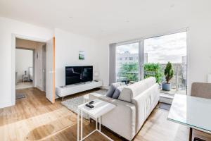 a white living room with a couch and a tv at Central Bournemouth Apartment, Balcony, Free Parking in Bournemouth