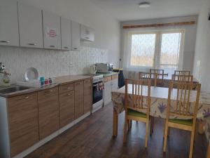 a kitchen with wooden cabinets and a table and chairs at Ubytovňa KARPATIA in Šaštín +26 photos