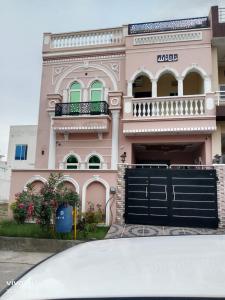 uma casa cor-de-rosa com um portão preto à frente. em Shah jee guest house em Jhelum