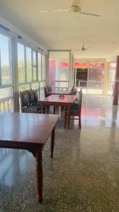 ein Esszimmer mit Tischen, Stühlen und Fenstern in der Unterkunft Goroomgo Hotel Casa Di William Khajuraho in Khajurāho