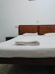 Una cama con sábanas blancas y almohadas. en Goroomgo Hotel Casa Di William Khajuraho, en Khajurāho