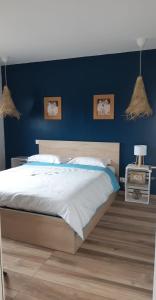 a bedroom with a large bed with a blue wall at Maison proche de la mer in Pianottoli-Caldarello +6 photos
