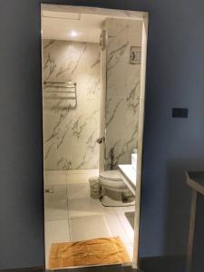 La salle de bains est pourvue de toilettes et d'un mur en marbre. dans l'établissement Diamond Park Inn Chiangrai & Resort, à Chiang Rai