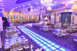 un salón de banquetes con mesas y sillas blancas y lámparas de araña en New Siesta Hotel & Resort en Alexandria