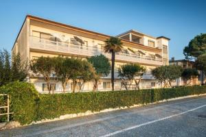 un grand bâtiment avec des arbres en face d'une rue dans l'établissement Cozy studio apartment with sea view - Beahost, à Lignano Sabbiadoro