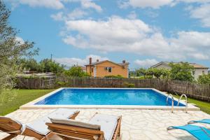 a swimming pool in a yard with chairs and a fence at Casa Mirna for 7 people near Pula with sea view & only 2 km from the sea in Peruški +40 photos