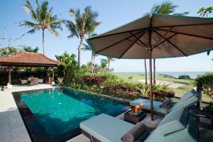 a swimming pool with an umbrella and chairs and a table at Villa Sundara in Tanah Lot