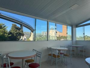 a row of tables and chairs in a room with windows at Pousada Bella Vista in Aparecida