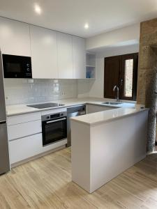 a kitchen with white cabinets and a sink at Casa A praciña, Playa de Soesto in Laxe