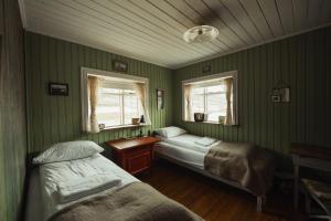a bedroom with two beds and a table and two windows at Wilderness Center / Óbyggðasetur Íslands in Óbyggðasetur
