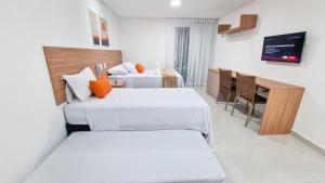a hotel room with two beds and a table at Sunset by AFT - PORTO DE GALINHAS in Porto De Galinhas