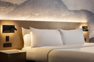 uma cama com almofadas brancas num quarto de hotel em Hôtel Québec Best Western PLUS Centre-Ville - City Center em Quebeque