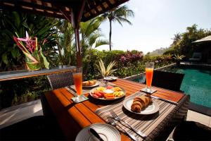 a wooden table with food and drinks and a pool at Villa Sundara in Tanah Lot