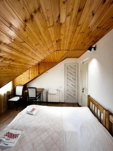 a bedroom with a large bed with a wooden ceiling at Nino & Irodi's Guest House in Kutaisi