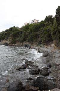 une plage rocheuse avec une maison sur une colline dans l'établissement Goddesses Villa 1 in Nies, à Soúrpi